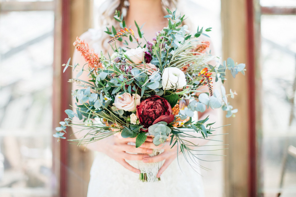 een mooie bruid die een boeket rode en witte bloemen vasthoudt