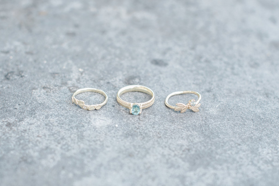 drie ringen met groene stenen op een betonnen oppervlak