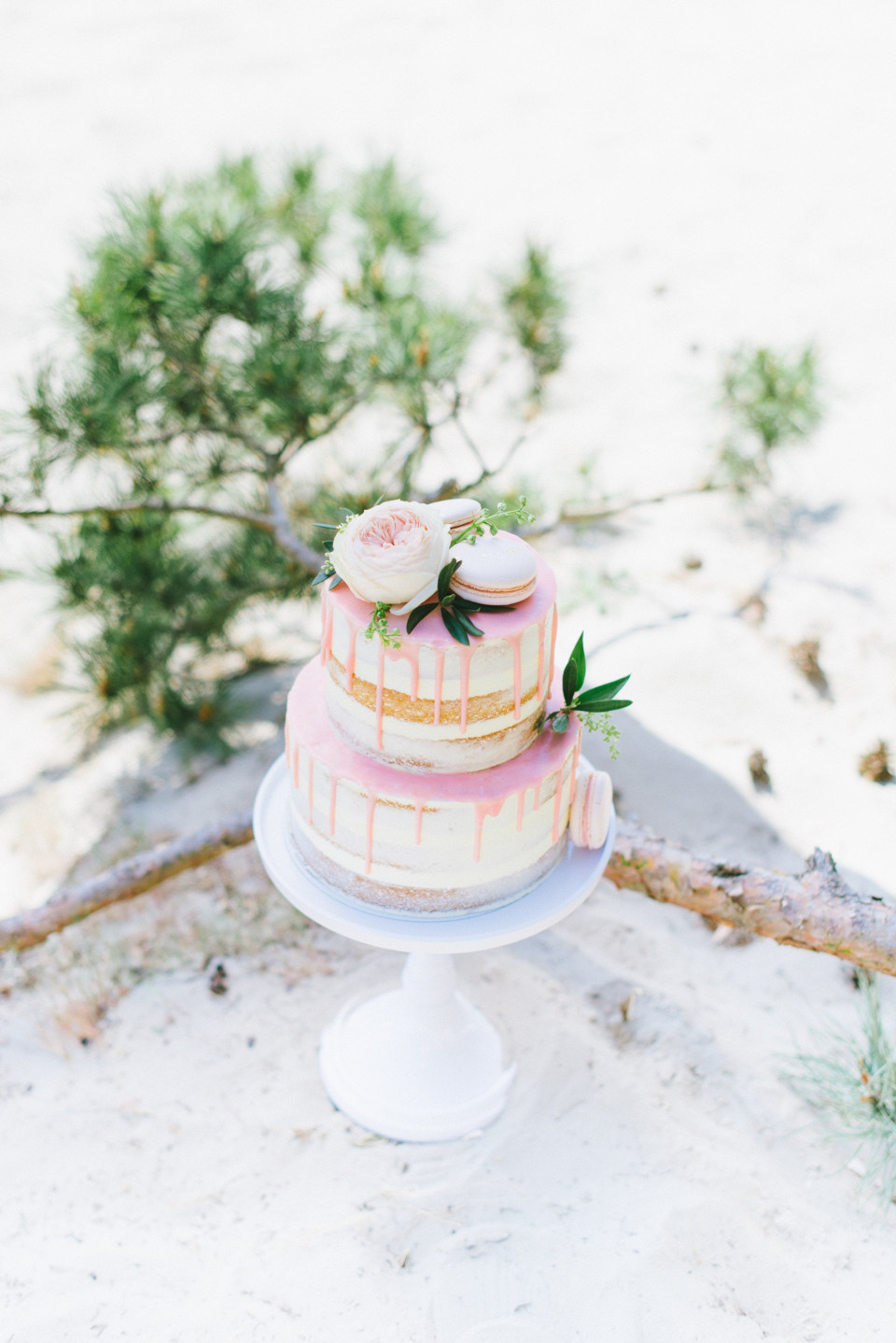 een roze en witte taart die op een strand staat