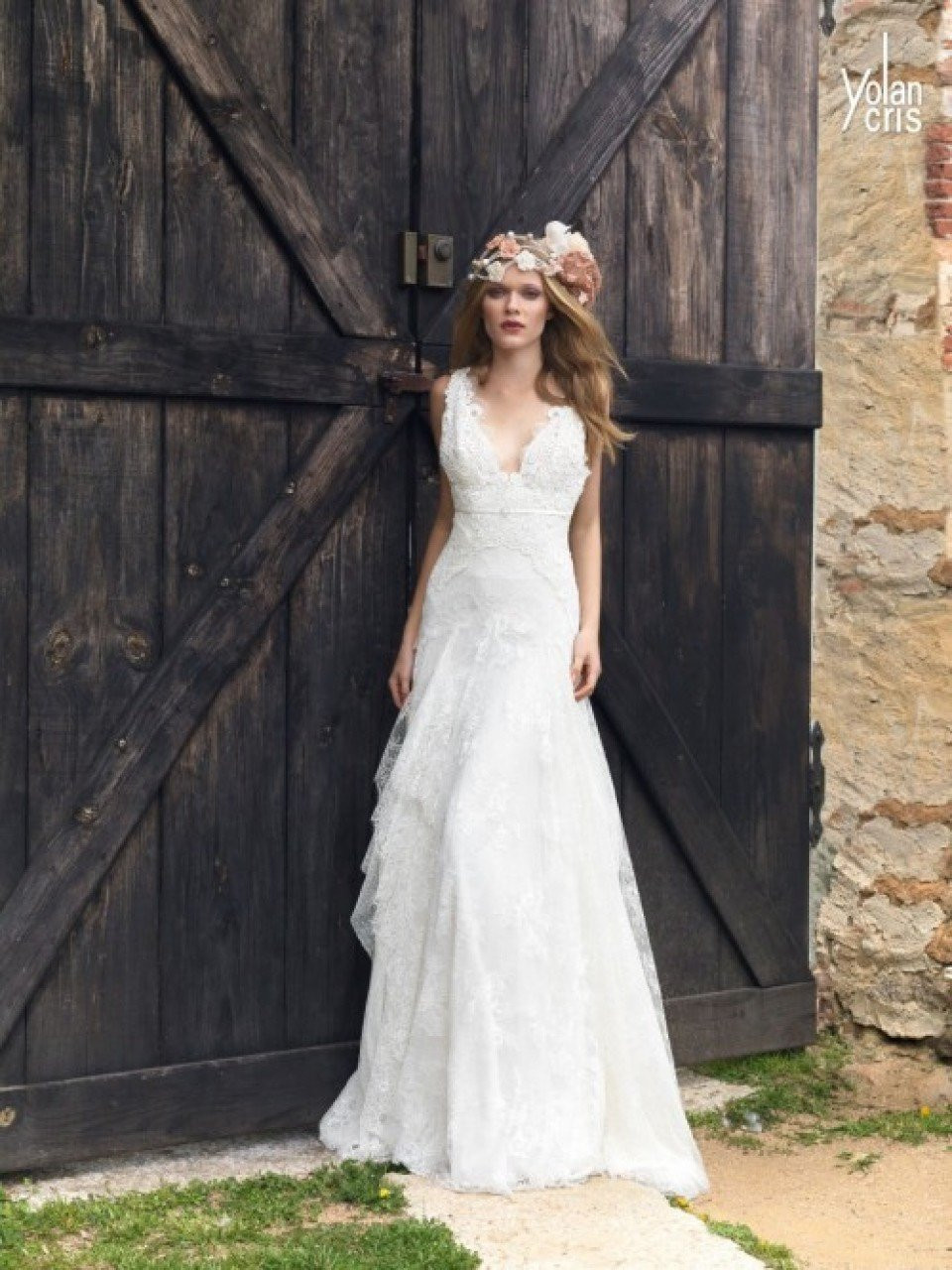 een mooie bruid in een trouwjurk staat voor een houten deur