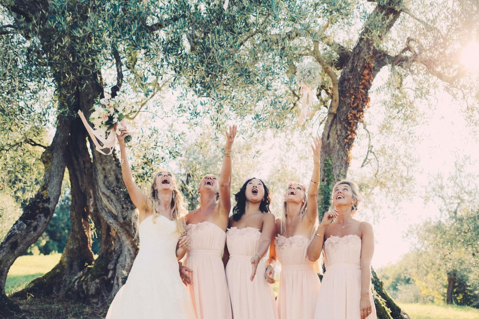 bruidsmeisjes in roze jurken die hun boeketten omhoog houden