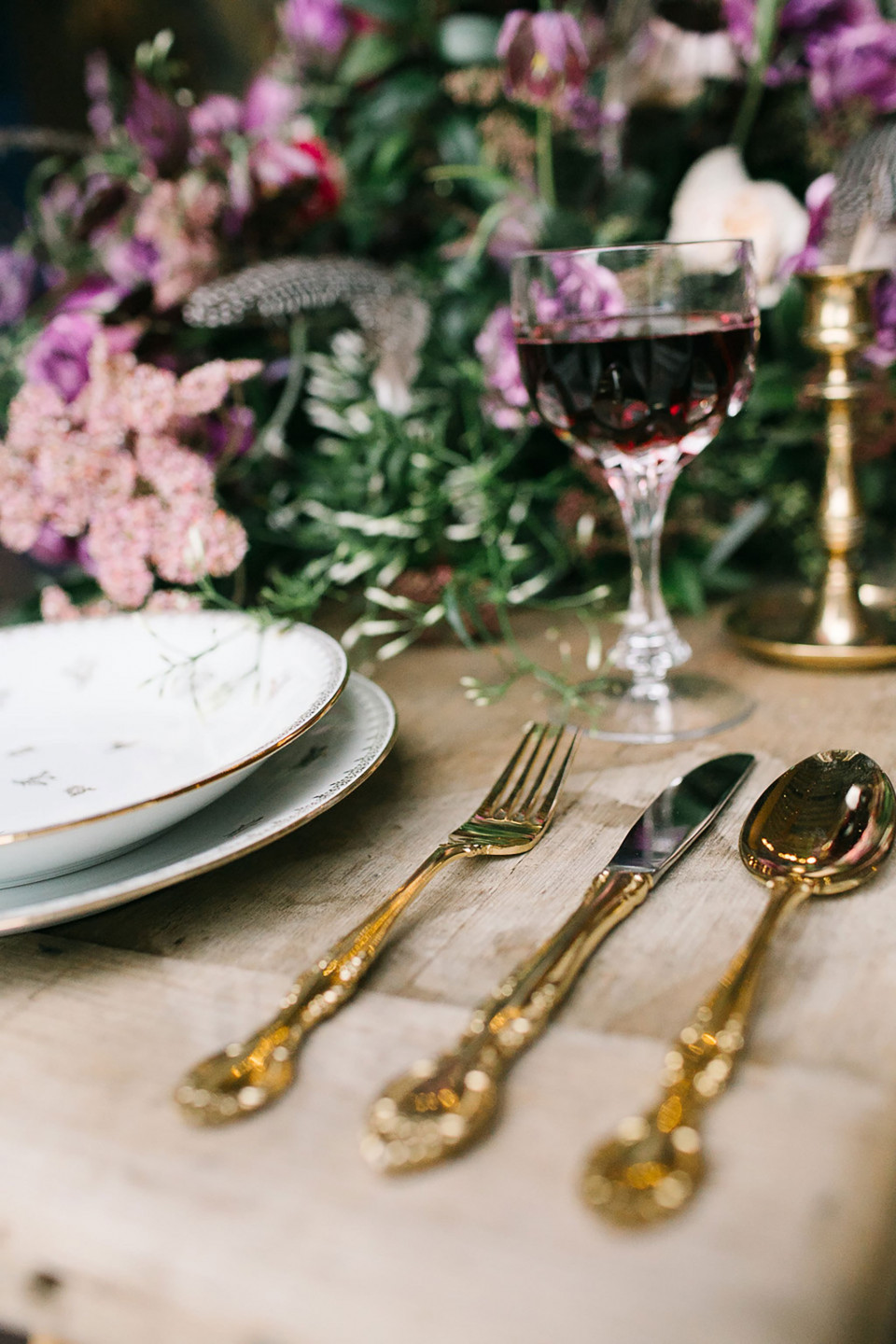 een tafelsetting met goud en paarse bloemen