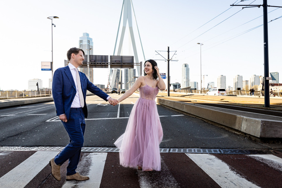 een man en een vrouw die over een zebrapad lopen in het midden van een stad met hoge gebouwen op de achtergrond