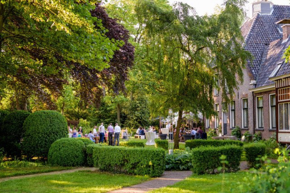 een tuin met bomen en struiken voor een huis