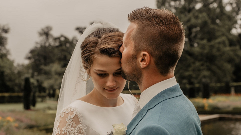 een bruid en bruidegom omhelzen elkaar voor een vijver