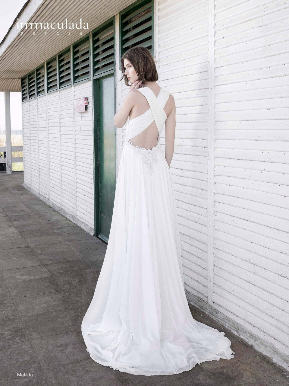 een vrouw in een witte jurk staande bij een gebouw