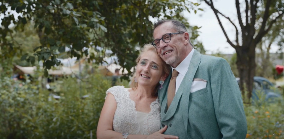 een man en vrouw in een groen pak en stropdas staan naast elkaar