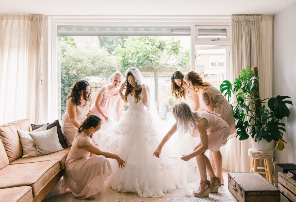 bruidsmeisjes helpen de bruid bij het aantrekken van de trouwjurk