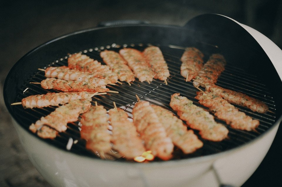 een grill met vlees aan spiesjes die erop koken
