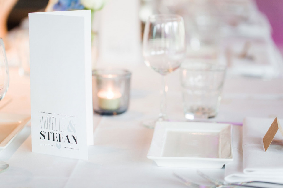 een tafel met witte tafelinstellingen en een plaatskaart