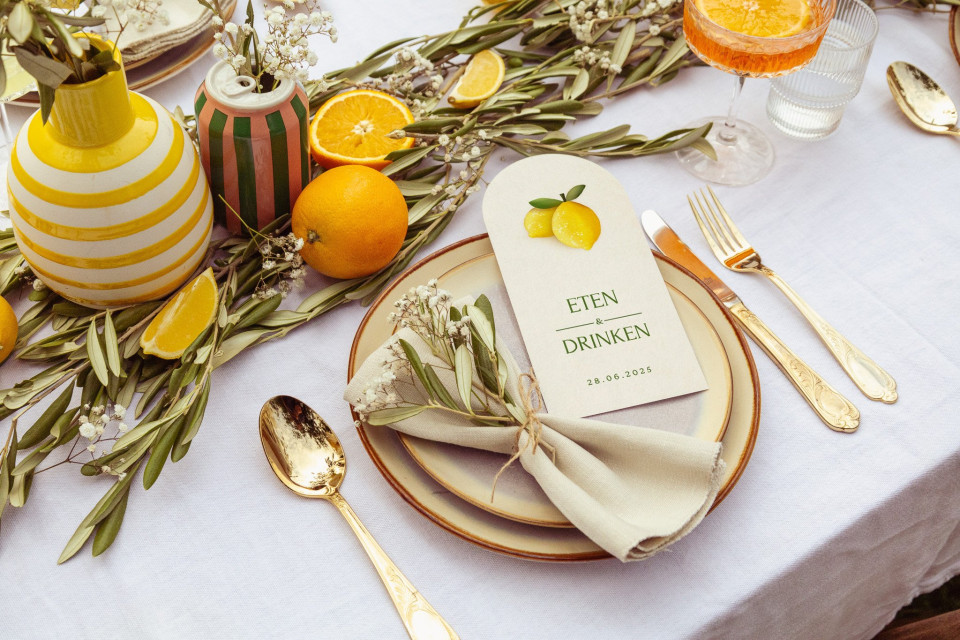 een afbeelding van een tafelsetting met sinaasappels, citroenen en bestek