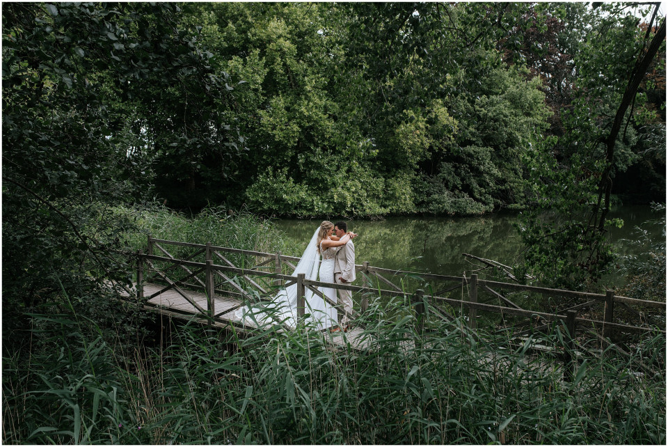 een bruid en bruidegom die op een brug bij het water staan