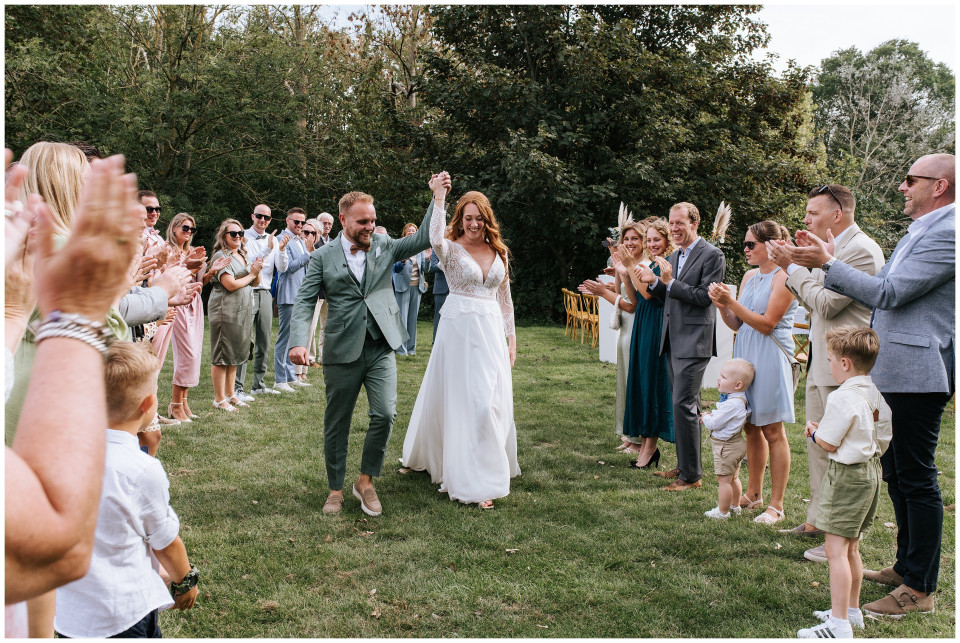 een bruid en bruidegom die het pad aflopen na hun huwelijksceremonie