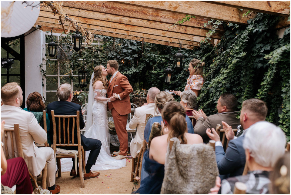 een bruid en bruidegom die zich aan het einde van hun trouwceremonie kussen