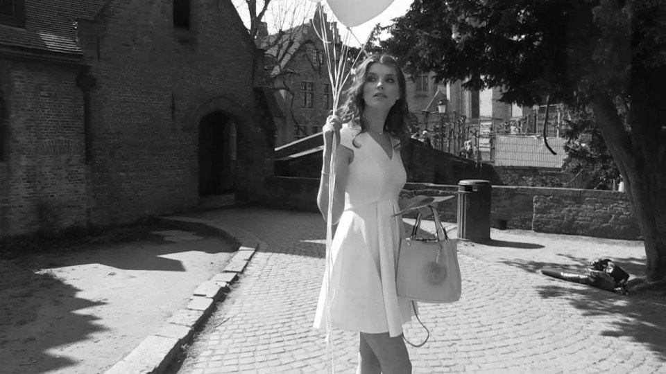 een vrouw in een witte jurk die ballonnen vasthoudt