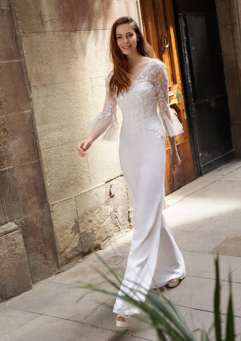 een vrouw in een witte trouwjurk die door een straat loopt