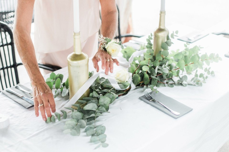 een vrouw die een tafel opzet met witte bloemen en groen
