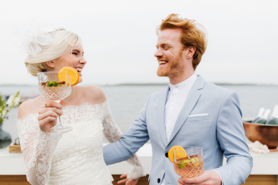 een bruid en bruidegom houden glazen sinaasappelsap vast