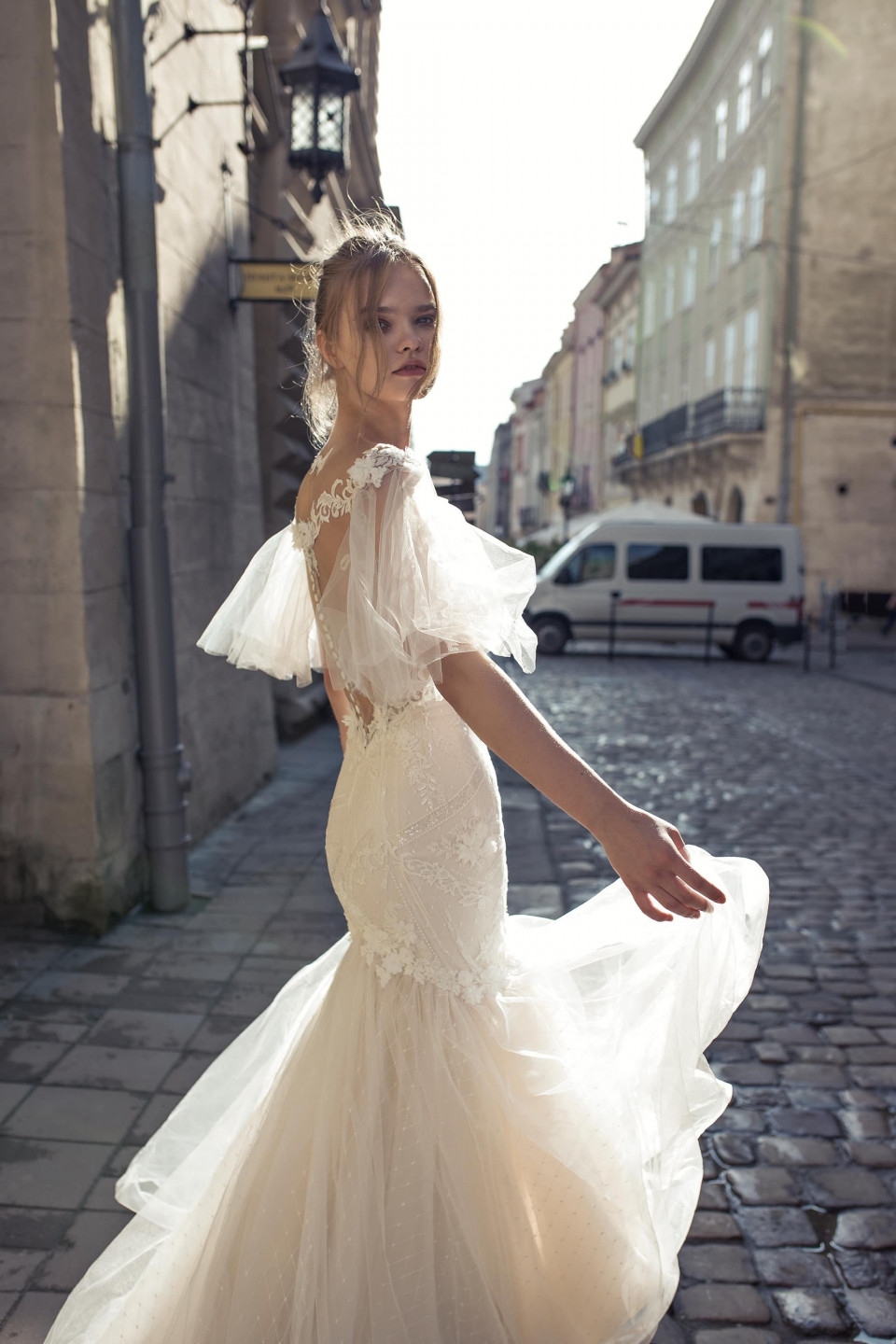 een vrouw in een trouwjurk loopt over een straat met keien