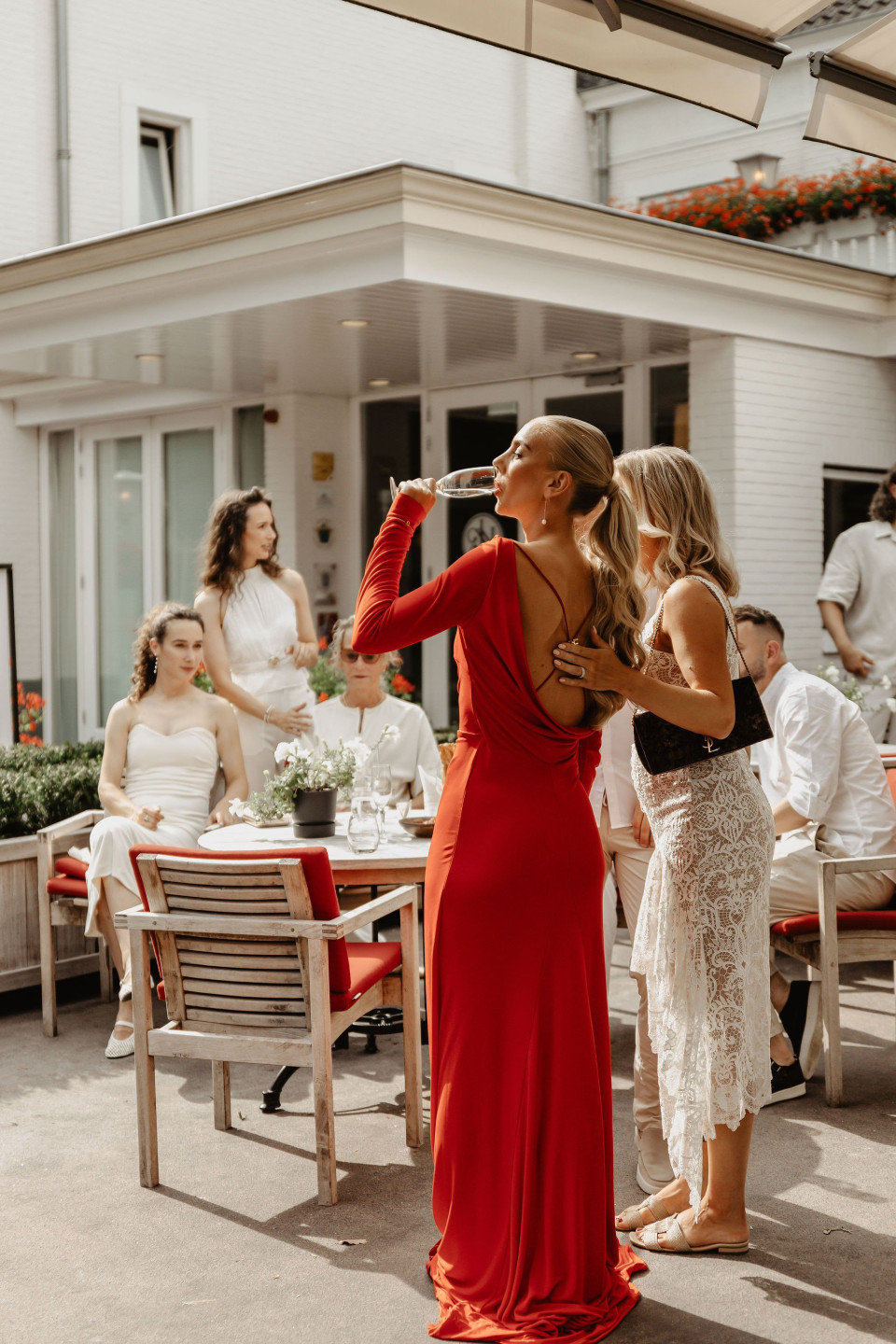 een vrouw in een rode jurk die een foto maakt met een mobiele telefoon