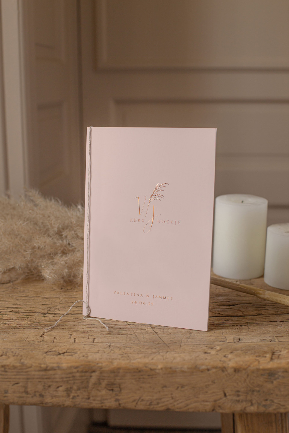 een roze notitieboek met een kaars op een houten tafel