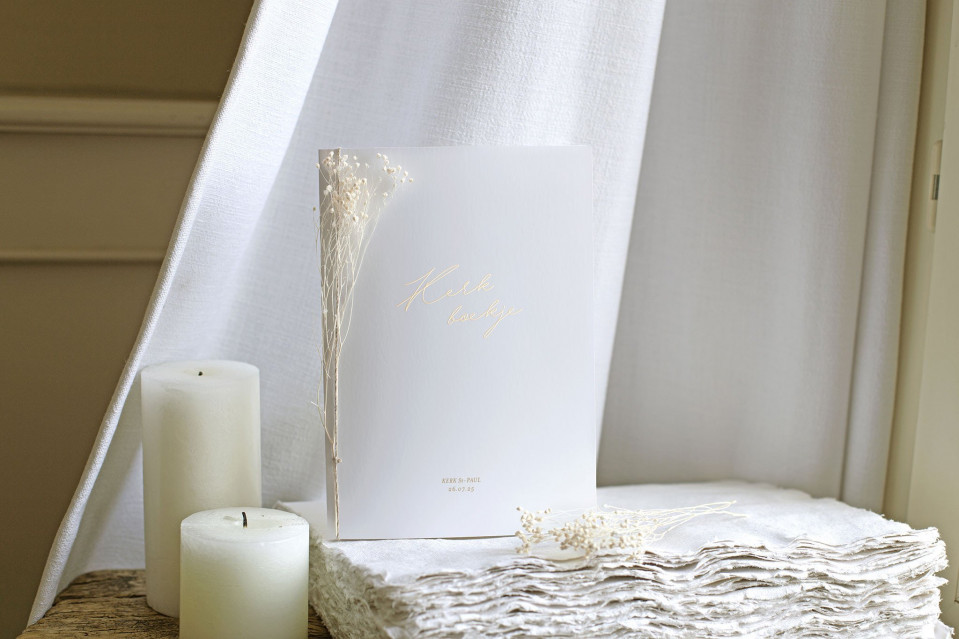 een witte kaars, een boek en een witte handdoek