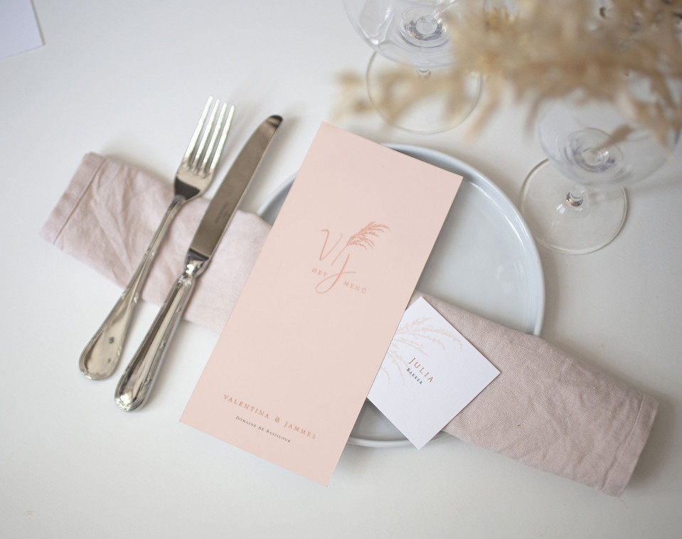 een roze servet en bestek op een witte tafel