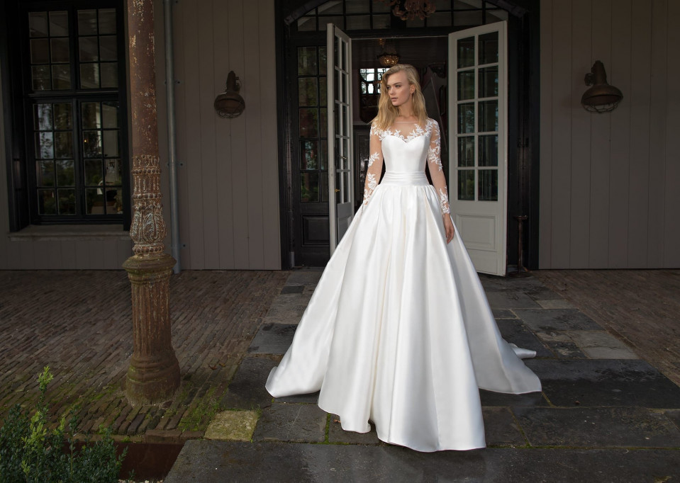 een vrouw in een trouwjurk staat voor een huis