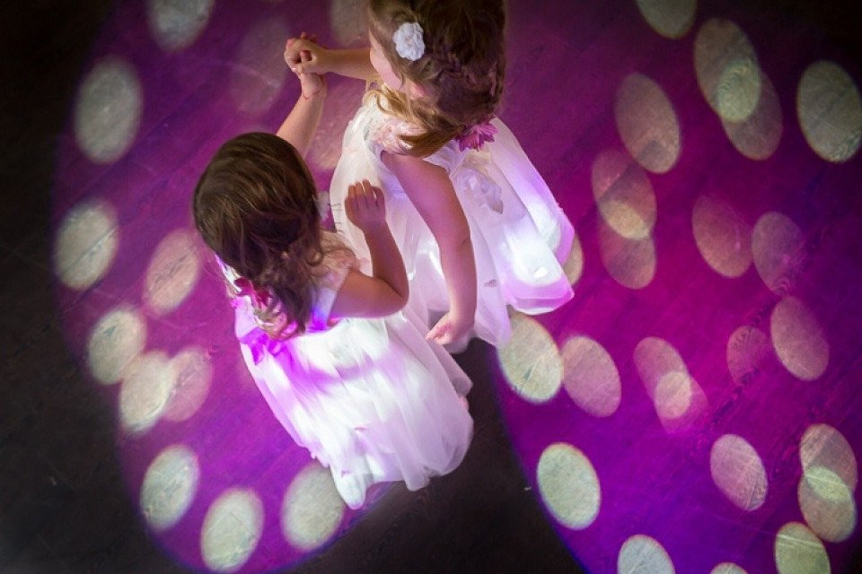 twee kleine meisjes in witte jurken dansen voor een paarse licht