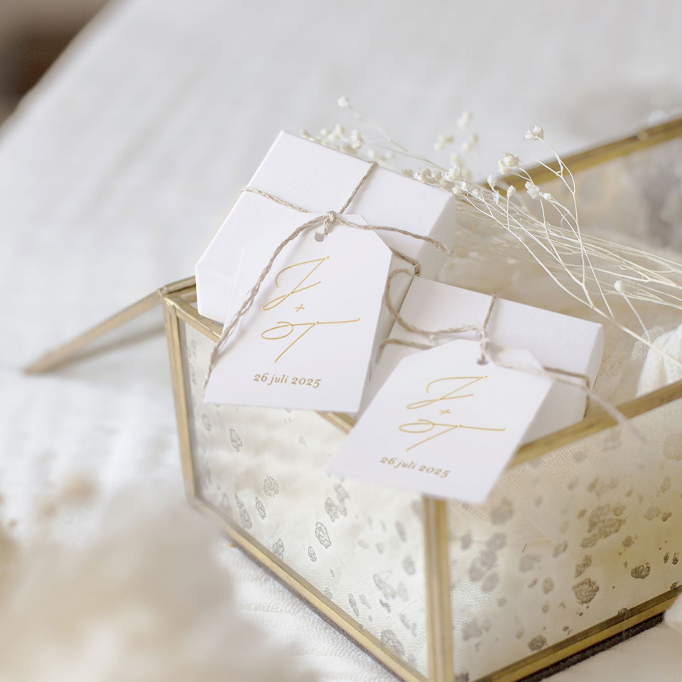 een doos met witte labels en bloemen op een bed
