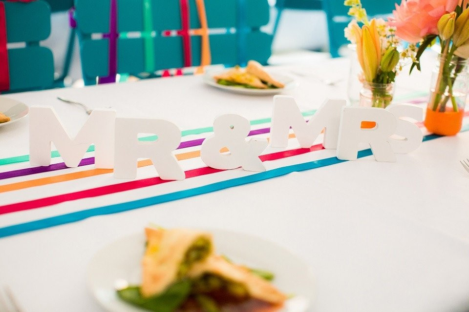 een tafel met kleurrijk tafelkleed en een bordje met mr en mrs erop