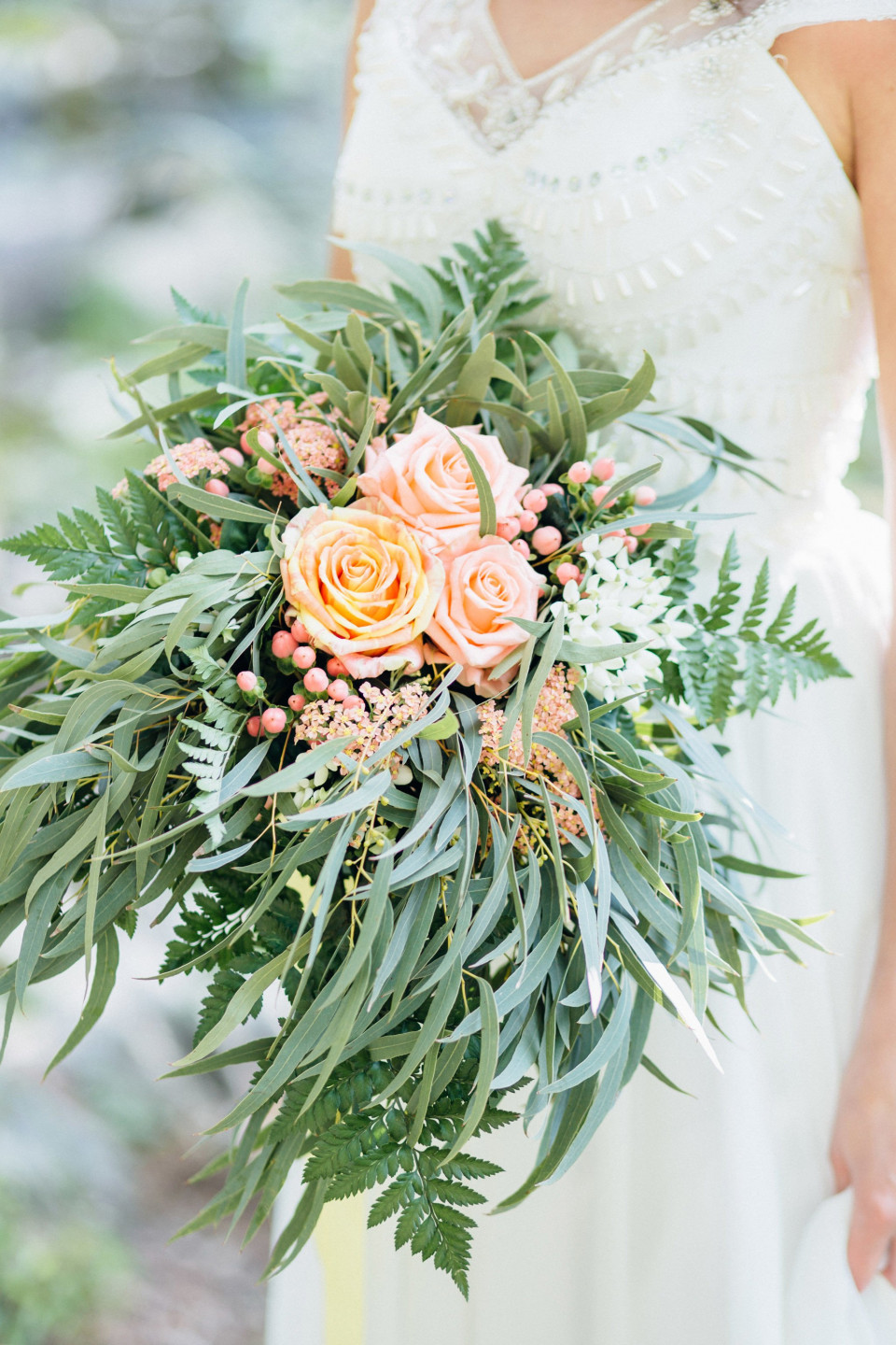 een mooie bruid die een boeket bloemen en groen vasthoudt