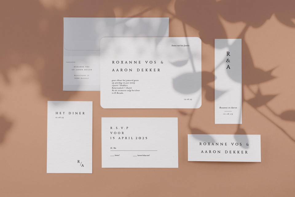 een trouwuitnodiging en briefpapier set op een beige achtergrond