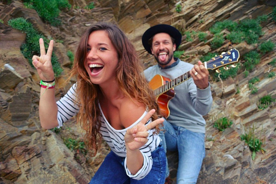 een man en vrouw poseren voor de camera terwijl ze gitaar spelen