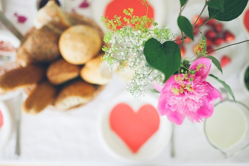een tafel met een hartvormig bord, bloemen en brood