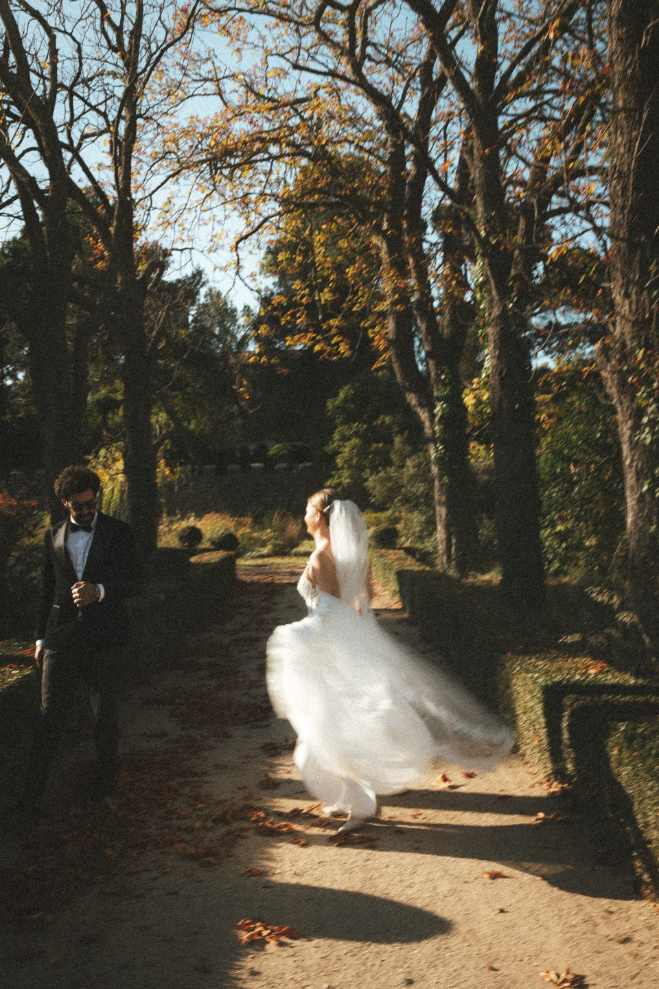 een bruid en bruidegom die een pad in een park aflopen
