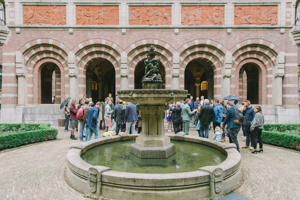 een groep mensen staat rond een fontein in een binnenplaats
