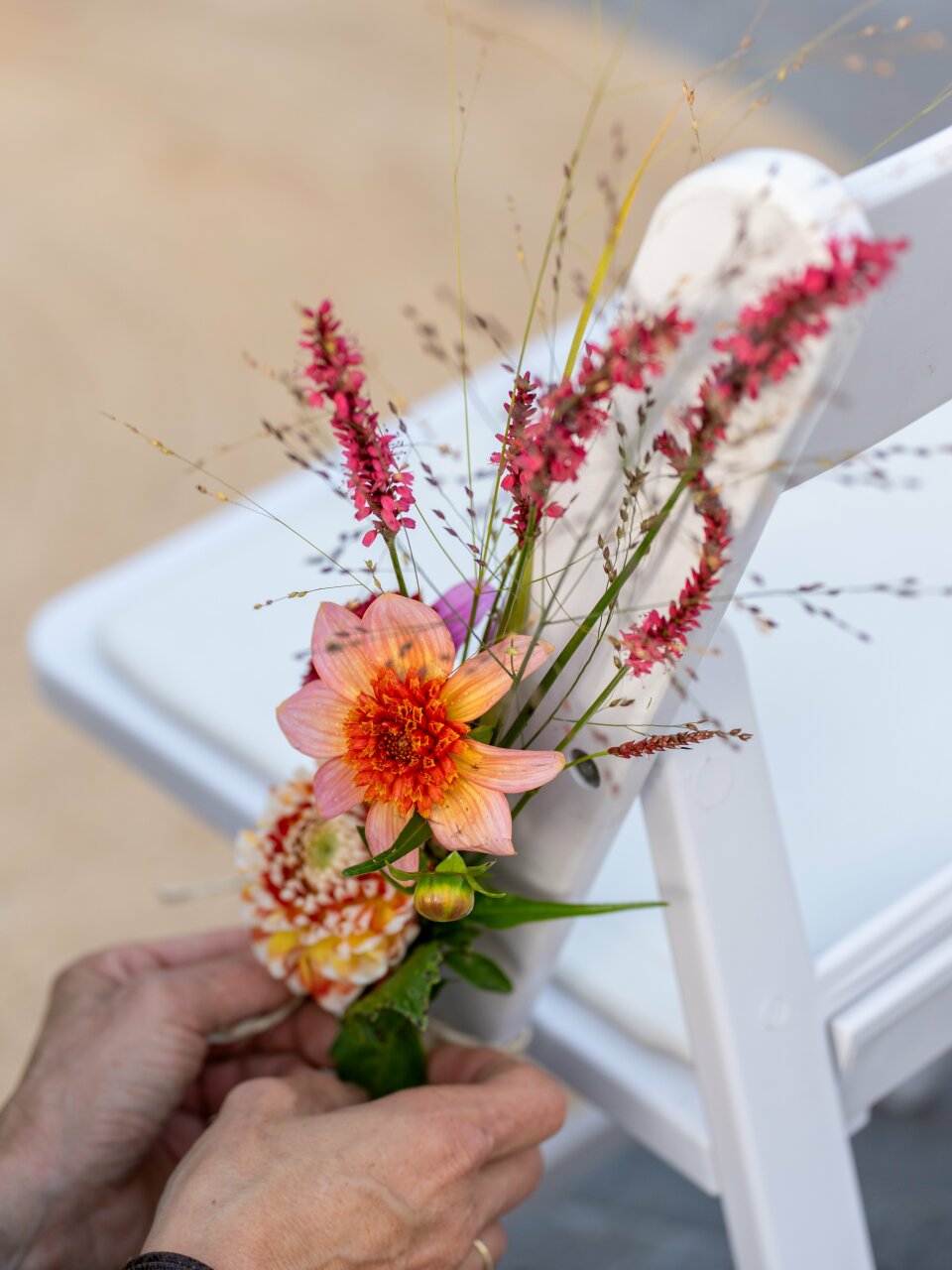 een persoon die een bloem op de rug van een witte stoel plaatst