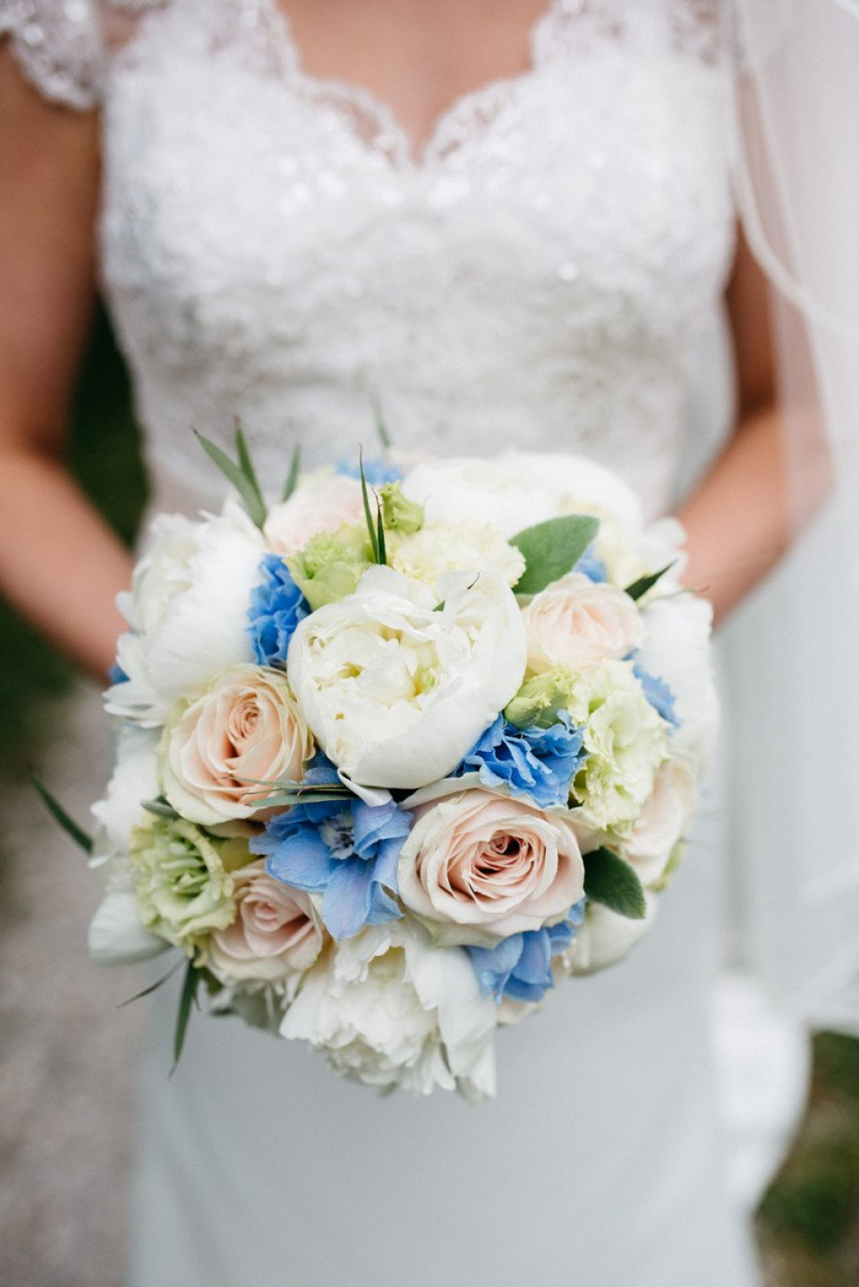 een bruid die een boeket witte en blauwe bloemen vasthoudt