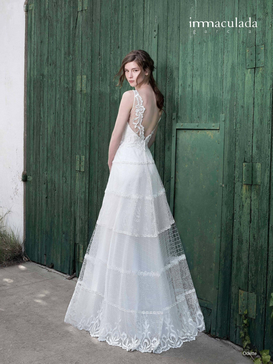 de achterkant van een vrouw in een trouwjurk staande voor een groene deur