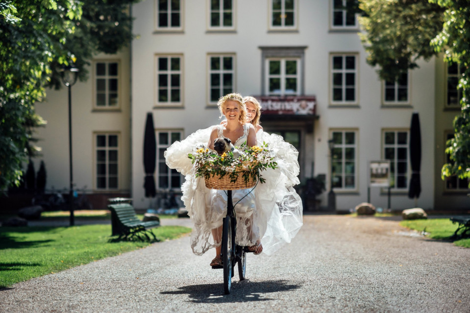 een bruid en bruidegom fietsen voor een groot gebouw
