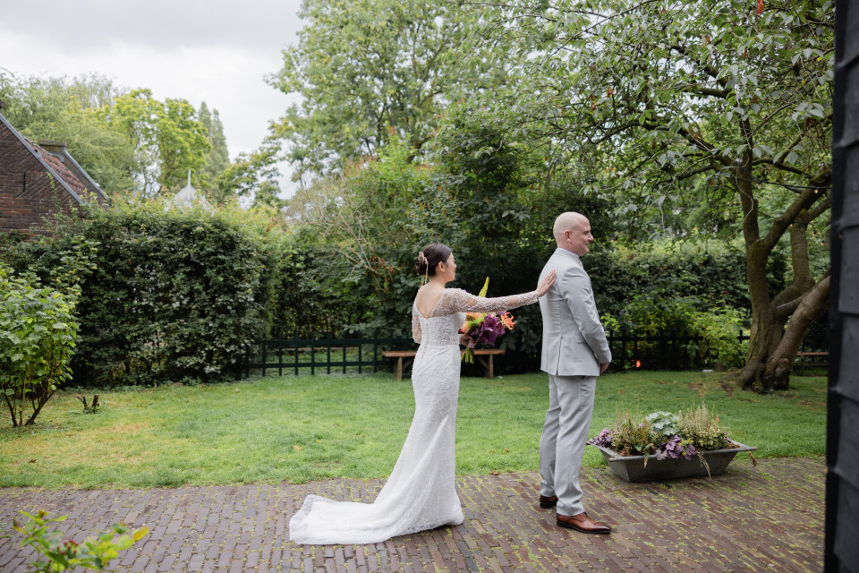 een bruid en bruidegom staan in de achtertuin van een huis