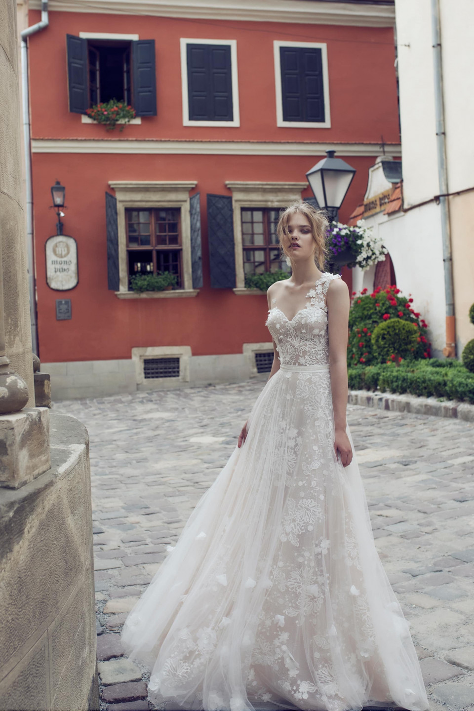 een vrouw in een trouwjurk staat voor een gebouw