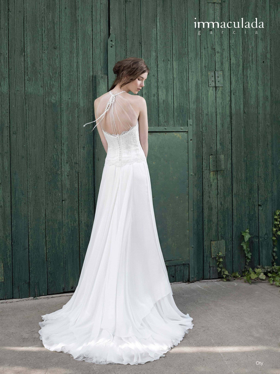 een vrouw in een witte trouwjurk staande voor een groene deur