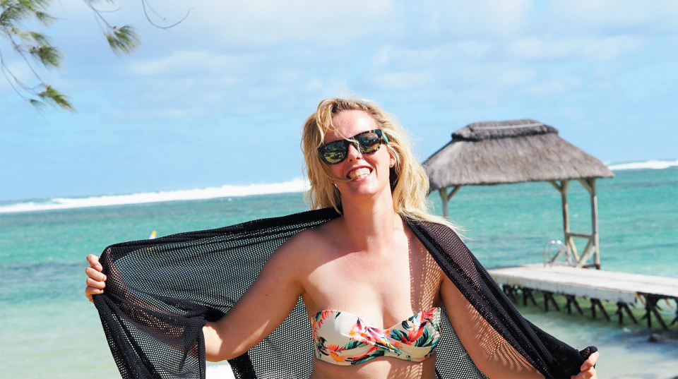 een vrouw in een bikini en zonnebril die op het strand staat