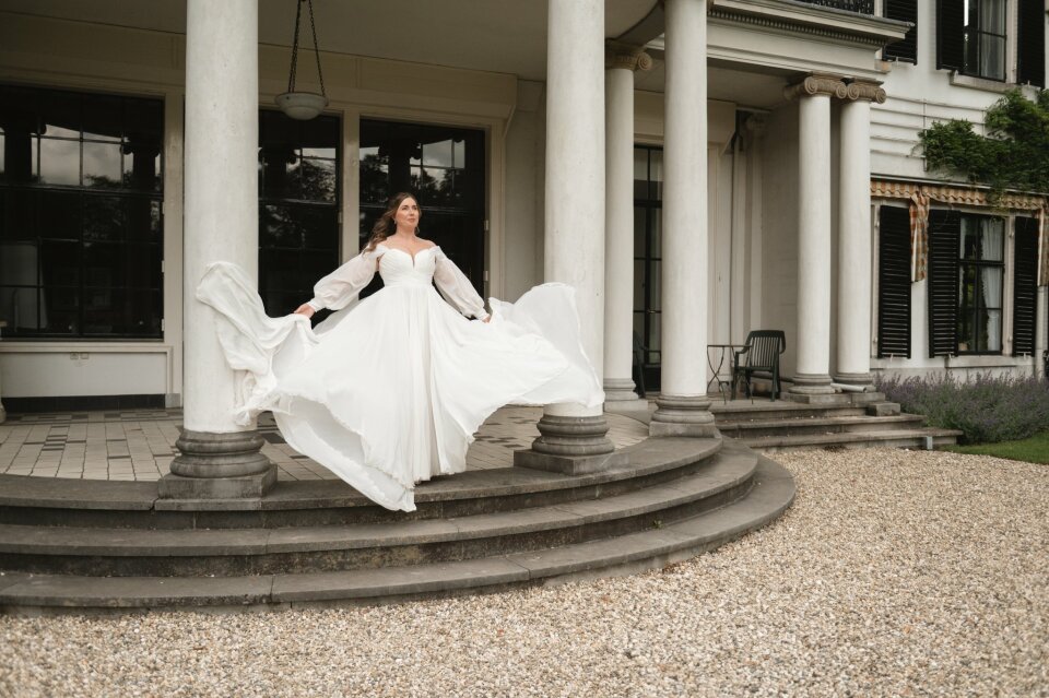 een vrouw in een trouwjurk op de treden van een huis