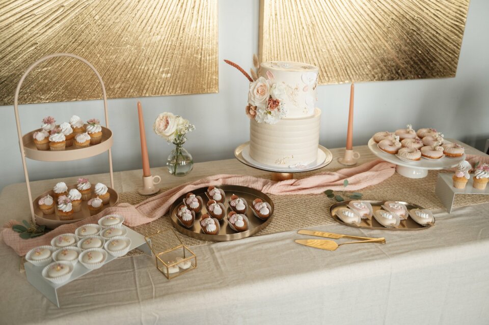 een tafel met een taart, cupcakes en andere desserts