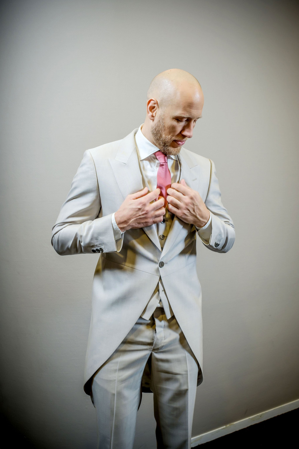 een kale man in een pak die zijn stropdas aanpast