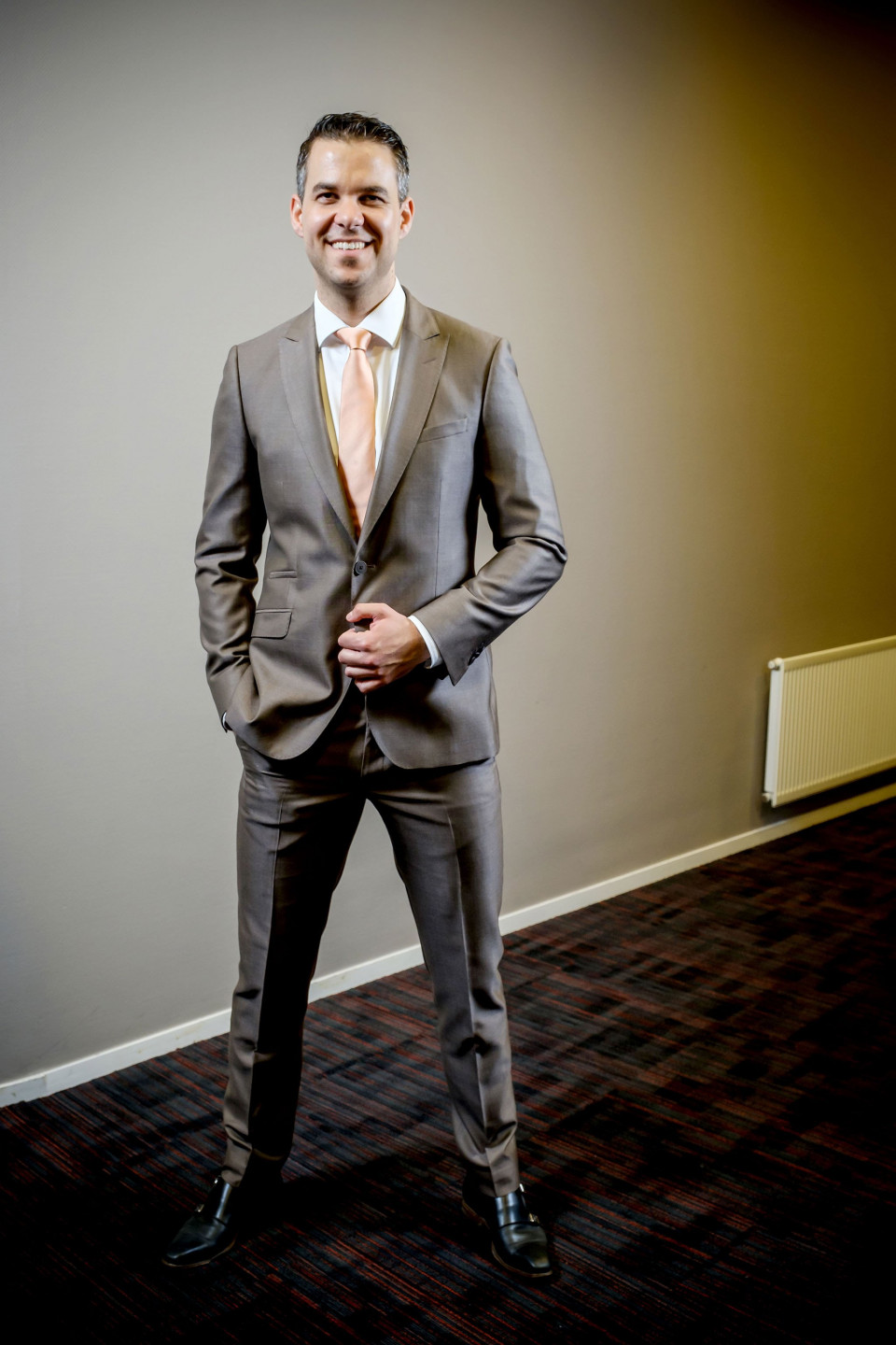 een man in een pak en stropdas die in een kamer staat