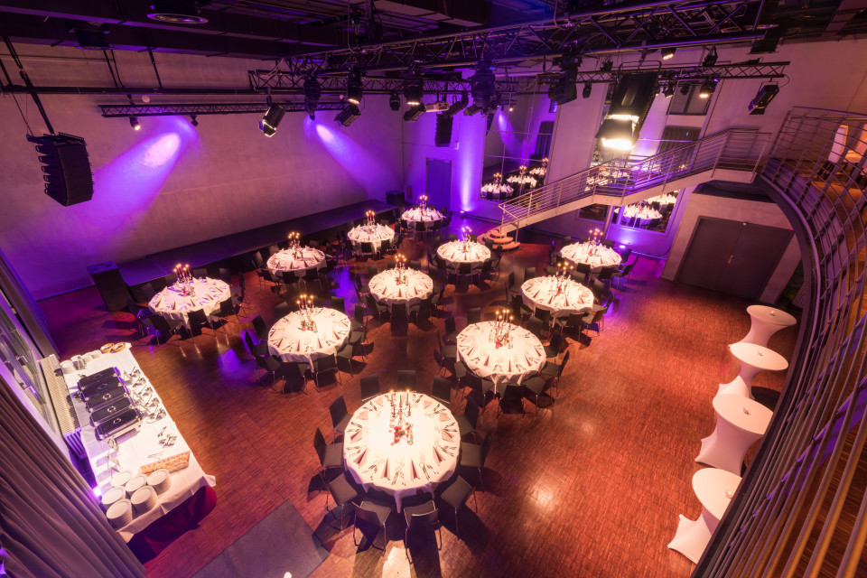 een binnen evenement met paarse verlichting en tafels